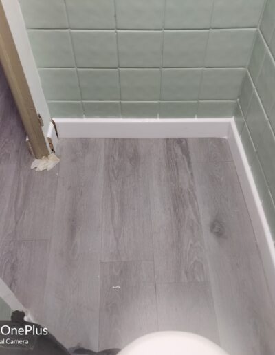 Pose de plinthes dans des WC après une pose de carrelage aux murs.